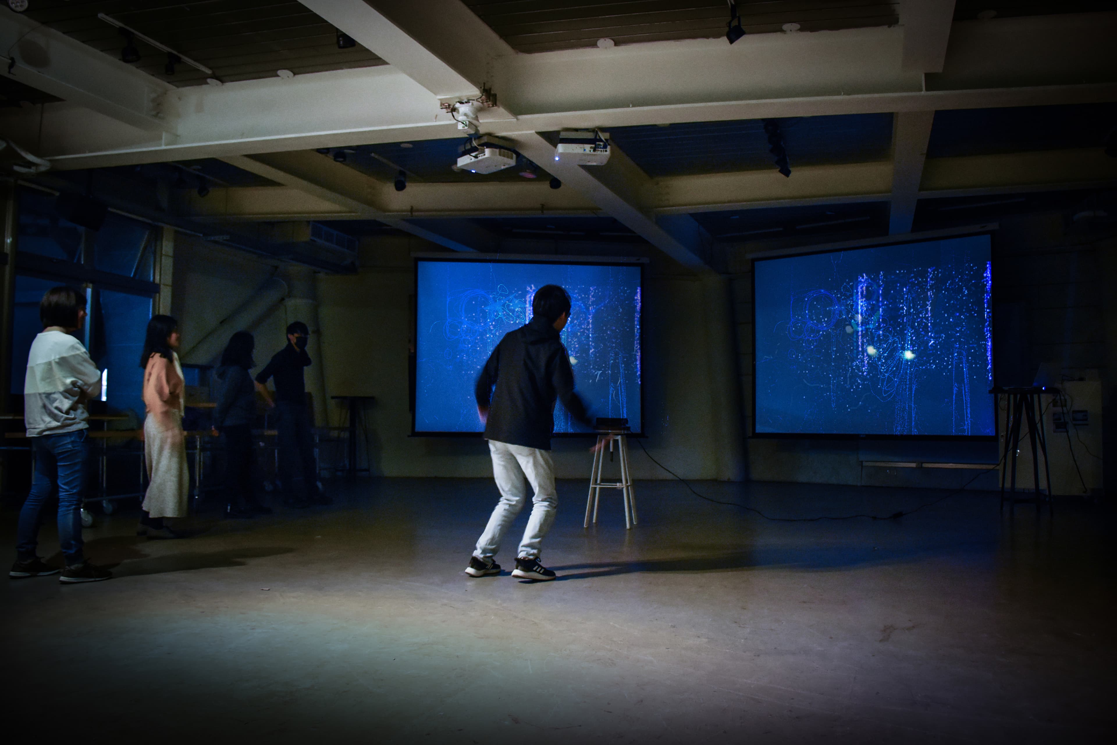 Person interacting with dual particle projections in a warehouse gallery